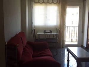 Salón con sofá, mesa y puerta al balcón