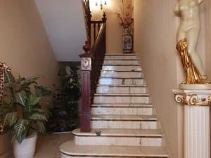 Escalera de mármol con barandilla de madera y escultura