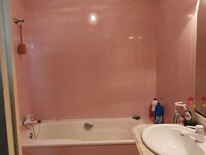 Baño con bañera y lavabo en tonos rosados
