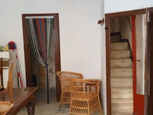 Estancia con sillones de mimbre y acceso a la escalera