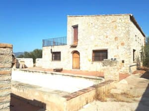 Casa de piedra con terraza en la cubierta y balsa delante