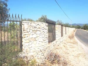 Muro de piedra con verja junto al camino