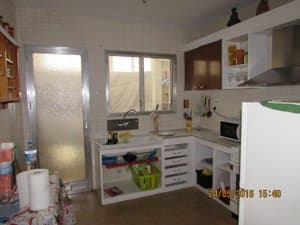 Cocina con muebles blancos, microondas y frigorífico