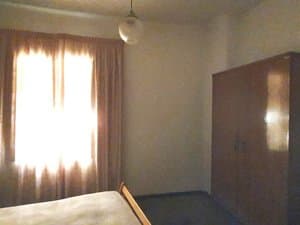 Dormitorio con armario y ventana con cortinas
