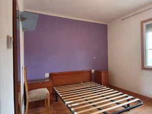 Dormitorio con pared lila y cabecero de madera