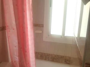 Baño con bañera, cortina y ventana