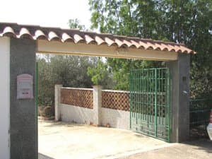 Entrada a la parcela con puerta de hierro y tejadillo