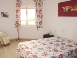 Dormitorio doble con butaca y ventana
