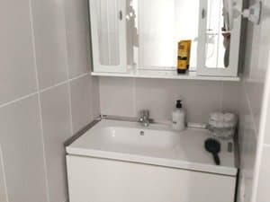 Baño con mueble de lavabo blanco y armario con espejo