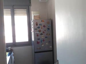 Cocina con frigorífico y ventana