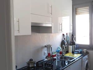 Cocina con muebles blancos, placa de gas y lavadora