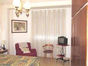 Dormitorio con butaca, televisor y armario