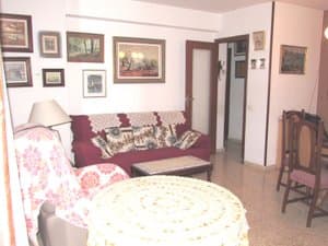 Salón con sofá, cuadros y mesa camilla