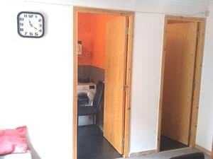 Comedor con reloj y puertas a la cocina y al baño