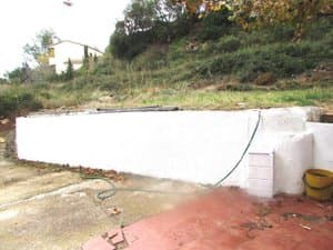 Patio con muro blanco junto al terreno