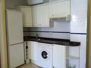 Cocina con muebles blancos, lavadora y frigorífico