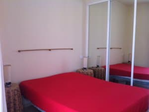 Zona de dormitorio con cama y armario de puertas de espejo