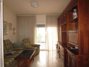 Salón con sofás, mueble de madera y salida a la terraza