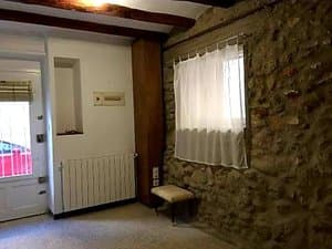 Sala con pared de piedra, radiador y ventana
