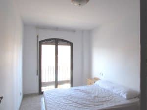 Dormitorio con cama y puerta balconera en arco