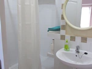 Baño con lavabo, espejo redondo y ducha con cortina