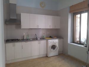 Cocina con muebles blancos, campana y lavadora