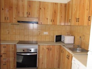 Cocina con muebles de madera, horno y microondas
