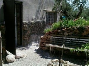 Entrada de la casa con bancal de piedra y banco