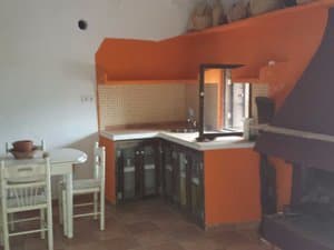 Cocina con muebles naranjas, mesa y chimenea