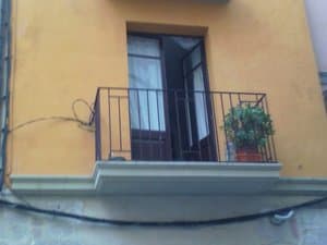 Fachada con balcón de hierro y maceta