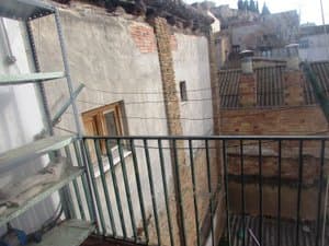 Balcón con estanterías y vistas a los tejados