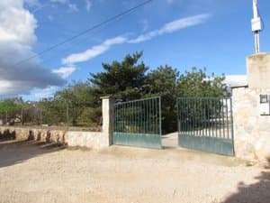 Puerta de acceso a la parcela con muro de piedra