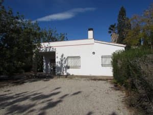 Casa blanca de una planta con camino de grava