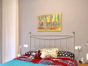 Dormitorio con cama de hierro y cuadro