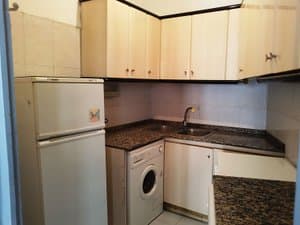 Cocina con frigorífico, lavadora y encimera de granito