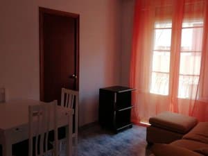 Comedor con mesa, sofá y ventana con cortinas