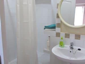 Baño con lavabo, espejo redondo y ducha con cortina