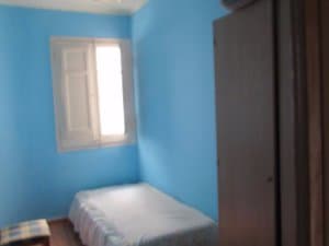Dormitorio de paredes azules con cama y ventana