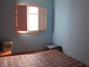 Dormitorio con cama y ventana con porticones