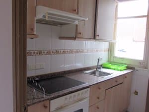 Cocina con placa vitrocerámica, horno y ventana