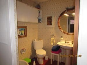 Baño con lavabo, espejo redondo e inodoro