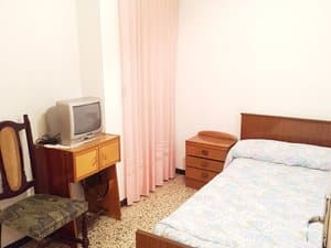 Dormitorio con cama, mesita y cortinas