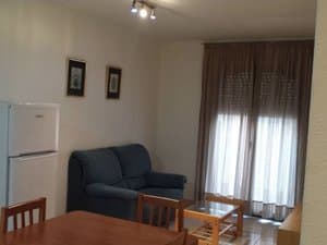 Cocina comedor con sofá, mesa, frigorífico y ventanal