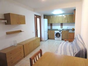 Comedor con sofá y cocina abierta con frigorífico y lavadora
