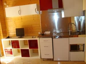 Cocina con microondas, frigorífico y paredes de madera