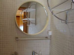Baño con espejo redondo y mosaico