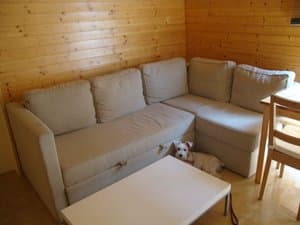 Salón con sofá rinconera y paredes de madera