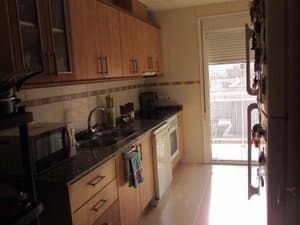 Cocina con muebles de madera y salida a la terraza