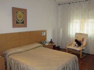 Dormitorio con cama de matrimonio y butaca