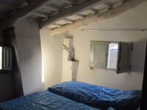 Dormitorio bajo cubierta con vigas y ventana